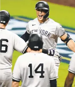  ?? JAE C. HONG AP ?? Yankees designated hitter Giancarlo Stanton (center) celebrates with teammates after hitting a grand slam in the ninth inning against the Rays on Monday.