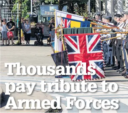  ??  ?? Standard bearers lower the flags in tribute as crowds enjoyed Armed Forces Day in Southport