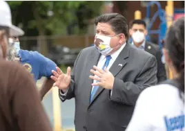  ??  ?? Gov. J.B. Pritzker speaks with people earlier this month during a visit to a COVID-19 testing station at Edward Coles School in South Chicago. SUN-TIMES FILE PHOTO