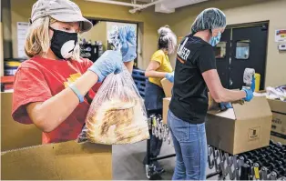  ?? GABRIELA CAMPOS/THE NEW MEXICAN ?? Alex Baker helps prepare boxes of food for public distributi­on at The Food Depot.
