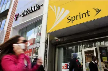  ?? Mark Lennihan/Associated Press ?? A woman using a cell phone walks past T-Mobile and Sprint stores in New York. Earlier this month, Sprint announced that it would stop selling location data to third parties.