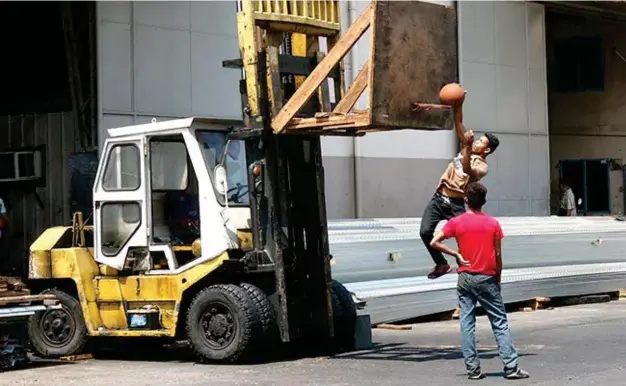  ?? (SETH DELOS REYES) ?? DAVAO. Workers take a break with a game of basketball, the ring hoisted up a forklift.