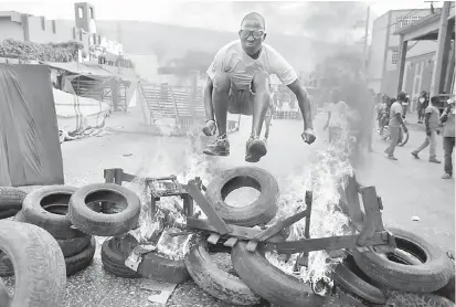  ?? — Gambar Reuters ?? MARAK: Seorang lelaki melompat di atas tayar yang terbakar semasa tunjuk perasaan terhadap kerajaan pimpinan Moise di jalan raya di Port-au-Prince, Haiti pada Ahad.