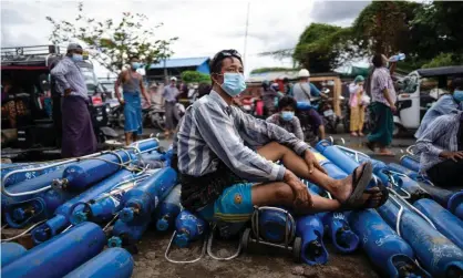  ?? Photograph: AFP/Getty Images ?? A man sits on empty oxygen canisters, as he waits to fill them up, outside a factory in Mandalay amid a surge in Covid-19 coronaviru­s cases in Myanmar