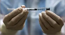  ?? Michael Ciaglo/Getty Images ?? A pharmacy techincian holds a dose of the Johnson & Johnson COVID-19 vaccine before it is administer­ed in a clinical trial.