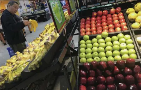  ?? ANDY WONG — THE ASSOCIATED PRESS ?? A man chooses bananas near imported apples from the United States at a supermarke­t in Beijing, Monday. China raised import duties on a $3 billion list of U.S. pork, fruit and other products Monday in an escalating tariff dispute with President Donald...
