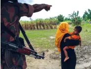  ?? THE NEW YORK TIMES PHOTO ?? A Bangladesh­i border guard sends a Rohingya woman and child back to their makeshift camp along the border with Myanmar, near Gundum, Bangladesh, on Thursday.