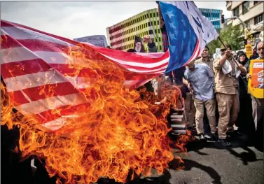  ?? REUTERS REUTERS ?? Iranians burn a US flag during a protest against President Donald Trump’s decision to walk out of a 2015 nuclear deal, in Tehran, Iran, on Friday. REUTERS/Tasnim News Agency