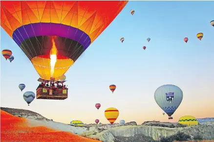  ??  ?? Up, up and away at sunrise in Cappadocia, where hot air balloons drift over a supernatur­al landscape.