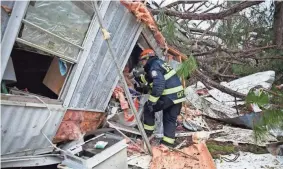  ?? ASSOCIATED PRESS ?? A rescue worker enters a hole in the back of a mobile home on Monday in Big Pine Estates in Albany, Ga. Fire and rescue crews were searching through the debris for tornado victims.