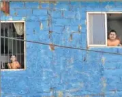  ?? REUTERS ?? Residents look out from the windows of their homes during a curfew n
in Colombo, Sri Lanka.