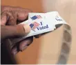  ?? PATRICK SEMANSKY, AP ?? A volunteer prepares to hand out stickers to voters at an early polling station in Towson, Md., on Nov. 1.