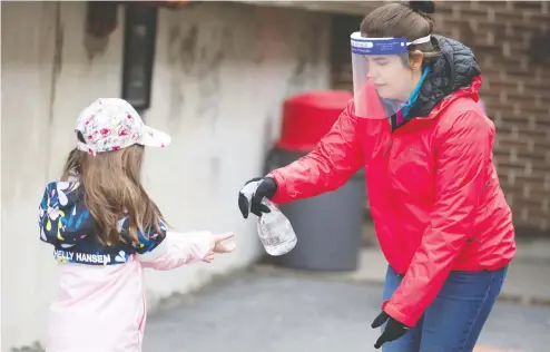  ?? CHRISTINNE MUSCHI / REUTERS FILES ?? A student has her hands sanitized as schools outside the greater Montreal region began to reopen their doors in May, a month that saw Quebec
turn to masks, hand sanitizer and distancing dots when it fully reopened most of its elementary schools.