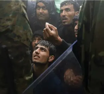  ?? YANNIS BEHRAKIS/REUTERS ?? Men beg Macedonian police to allow them to enter the country from Greece during a rainstorm near the Greek village of Idomeni on Thursday. More than 7,000 people crossed the border into Macedonia on Thursday.