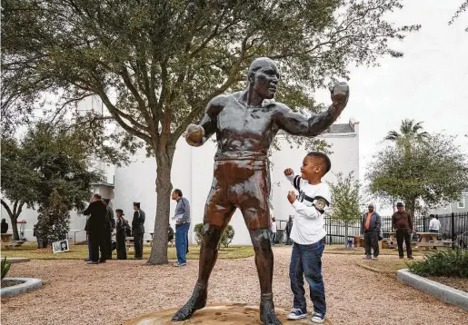  ?? Houston Chronicle file ?? Spencer Collins boxes with a statue of Jack Johnson at Galveston’s Jack Johnson Park during the 2014 dedication ceremony of a historical marker honoring the Galveston native who became the first Black world heavyweigh­t champion.
