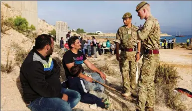  ??  ?? Watching brief: British servicemen keep an eye on migrants who arrived by boat at RAF Akrotiri