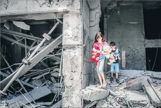  ?? ANAS BABA / AFP ?? Dos niños llevándose ayer peluches de su vivienda situada en la torre Al Yauhara de Gaza, bombardead­a por los misiles israelíes