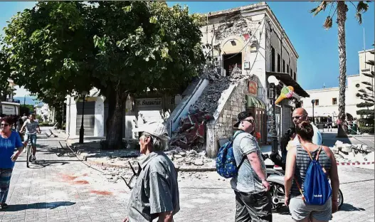  ??  ?? Ruined holiday: Tourists gathering beside ruined buildings on the island of Kos following the earthquake which struck the region. — AFP