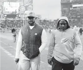  ?? JAMES KENNEY/AP ?? Dolphins head coach Brian Flores, left, walks off the field Sunday after a loss to the Titans in Nashville, Tennessee.