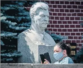  ?? YURI KADOBNOV / AFP ?? Una mujer pasa junto al busto de Stalin en los muros del Kremlin