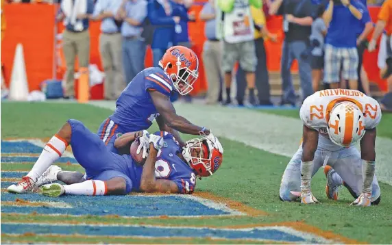  ?? THE ASSOCIATED PRESS ?? Florida’s Tyrie Cleveland, bottom left, celebrates his game-winning touchdown with fellow wide receiver Brandon Powell as Tennessee defensive back Micah Abernathy hangs his head in despair after the Vols lost 26-20.