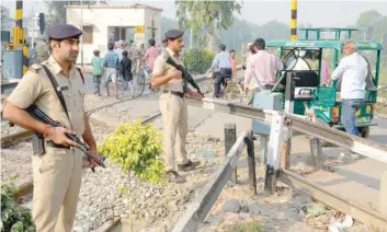  ??  ?? Police stand guard near a railroad crossing as commuters pass by, three days after a train accident in the area, in Amritsar on Monday. — AFP