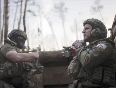  ?? (AP/Alex Babenko) ?? A Ukrainian serviceman from the Azov brigade known by his call sign “Chaos” (right) holds a mortar shell while he waits for a command to fire at a position about a half mile away from Russian forces on the front line in Kreminna, Donetsk region, Ukraine, on Friday.