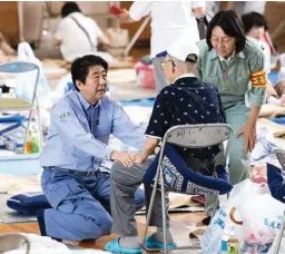  ??  ?? Japan's Prime Minister Shinzo Abe (C) visits a shelter for people affected by the recent flooding in Mabi, Okayama prefecture on July 11, 2018. The toll in record rains that have devastated parts of Japan has risen to 179, the government's top...