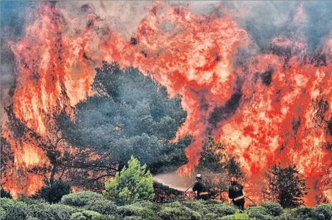  ?? ANGELOS TZORTZINIS / AFP ?? Los bomberos, como estos que trabajan en el incendio de Kinetia, cerca de Atenas, hicieron frente a rachas de viento de hasta 100 kilómetros por hora