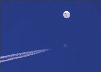  ?? CHAD FISH THE ASSOCIATED PRESS ?? A large balloon drifts above the Atlantic Ocean, just off the coast of South Carolina, with a fighter jet and its contrail seen below it. The balloon was struck by a missile from an F-22 fighter just off Myrtle Beach.
