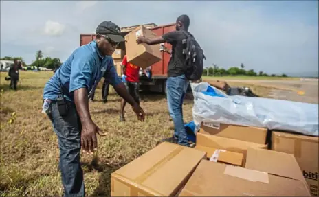  ?? Richard Pierrin/Getty Images ?? Haitians load a truck with medical gear flown in from the United States on Thursday at Antoine Simon airport in Les Cayes, Haiti. Rescue efforts continue among destroyed homes after the quake struck on Saturday.