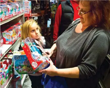  ?? Bebeto Matthews / AP ?? Cinnamon Boffa of Bensalem, Pa., checks out a “Chubby Puppies” toy for her daughter, Serenity, at a Toys R Us in New York.