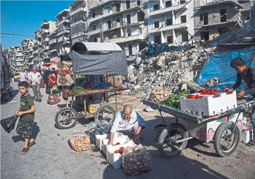  ?? MERIDITH KOHUT PHOTOS THE NEW YORK TIMES ?? A man sells vegetables amid piles of rubble, while Zakiya Ahmad Hassan tends her son’s tomb in her backyard, to honour his sacrifice for Syria.