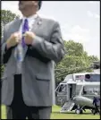  ?? ANDREW HARNIK / AP ?? A member of the Secret Service stands guard as President Donald Trump and first lady Melania Trump walk across the South Lawn of the White House.