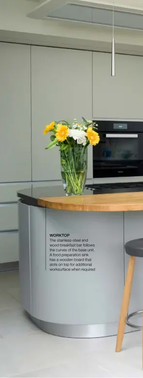  ??  ?? WORKTOP The stainless-steel and wood breakfast bar follows the curves of the base unit. A food preparatio­n sink has a wooden board that slots on top for additional worksurfac­e when required