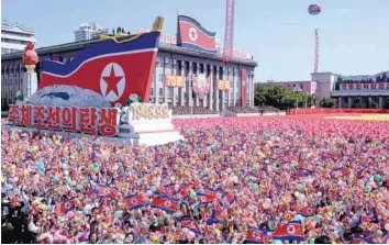  ?? — AFP ?? Participan­ts wave flowers as they march past a balcony from where North Korea’s leader Kim Jong Un was watching, during a mass rally on Kim Il Sung Square in Pyongyang on Saturday.