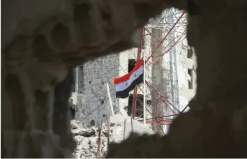  ?? AFP ?? The Syrian national flag rises in the midst of damaged buildings in Daraa al Balad, an opposition-held part of the southern city of Daraa, on Thursday. —