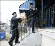  ?? MATT ROURKE - THE ASSOCIATED PRESS ?? Officers Brian Dillard, left, and Robert Saccone carry a police donated Thanksgivi­ng meals to a resident’s home in Philadelph­ia on Tuesday.