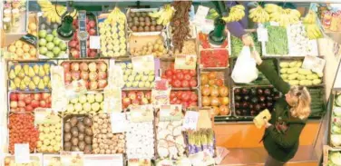  ?? Reuters ?? ↑
A woman buys fruits and vegetables at a food market in the capital of Seville, southern Spain.