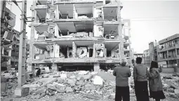  ??  ?? In this photo provided by the Iranian Students News Agency, ISNA, people look at destroyed buildings after an earthquake at the city of Sarpol-e-Zahab in western Iran. (AP Photo)