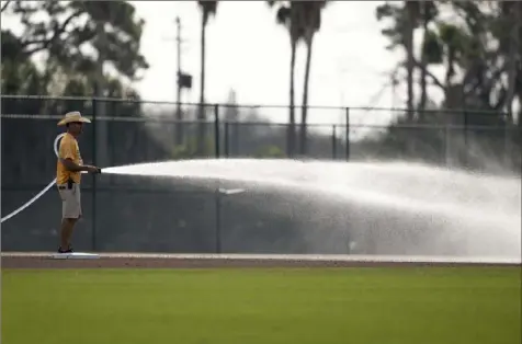  ?? Benjamin B. Braun/Post-Gazette ?? A worker sprays the field at Pirate City before Pirates players participat­e in spring training on Friday in Bradenton, Fla.