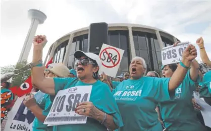  ??  ?? Lydia Balderas, left, and Merced Leyua, right, join others outside the Federal Courthouse in San Antonio on Monday to oppose a new Texas “sanctuary cities” bill that aligns with the president’s immigratio­n stance. Eric Gay, The Associated Press