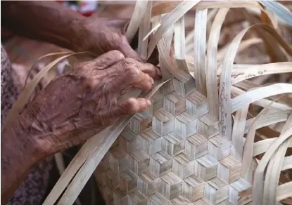  ??  ?? Seorang mama sedang menganyam kapowen, semacam tas pandan berpola heksagonal, untuk dijual.