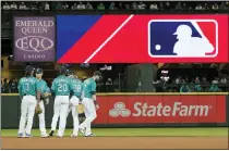  ?? ASSOCIATED PRESS FILE PHOTO ?? Seattle Mariners gather as the MLB logo is shown during a review of an attempted catch by right fielder Mitch Haniger of a ball hit by Tampa Bay Rays’ Ji-man Choi that was originally called an out during the ninth inning of a June 18 game in Seattle.