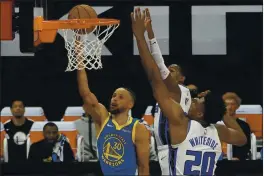  ?? RICH PEDRONCELL­I — THE ASSOCIATED PRESS ?? Golden State Warriors guard Stephen Curry, left, goes to the basket against Sacramento Kings’ De’Aaron Fox, center, and Hassan Whiteside during the first quarter in Sacramento on Thursday.