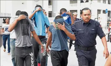  ??  ?? Day in court: The four teenagers being escorted by the police to the magistrate’s court in George Town, Penang.