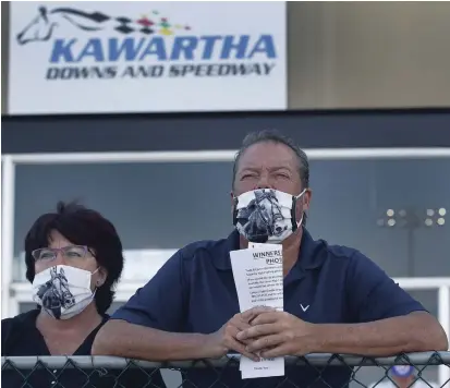  ?? CLIFFORD SKARSTEDT EXAMINER FILE PHOTO ?? Spectators wear matching horse design masks while taking in the harness racing action at Kawartha Downs on Aug. 15. The Fraservill­e track has reached a new five-year funding agreement with the province.