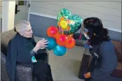  ??  ?? Rosa Gomez Gracida, right, delivers balloons to Pacifica Senior Living resident Beverly Hensel. With residents not having visitors over the last year, Pacifica has hosted community events to bring smiles to its seniors.