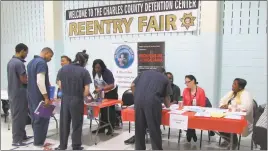  ?? STAFF PHOTO BY ANDREW RICHARDSON ?? Inmates at the Charles County Detention Center’s fourth annual re-entry fair speak with representa­tives of the Life Journeys Writers Guild, to the left, and Department of Health, to the right.