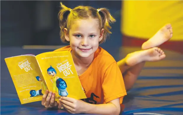  ?? Picture: BRENDAN RADKE ?? DELIGHTFUL YARN: Junior gymnast Haydyn Scoble, 8, of Edmonton, reads Inside Out, part of the My Magical Story Collection of Disney storybooks.